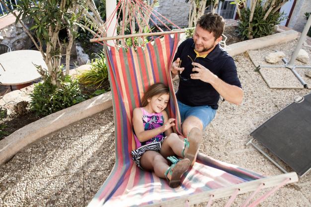 nina-tumbada-hamaca-junto-su-padre_23-2147624086